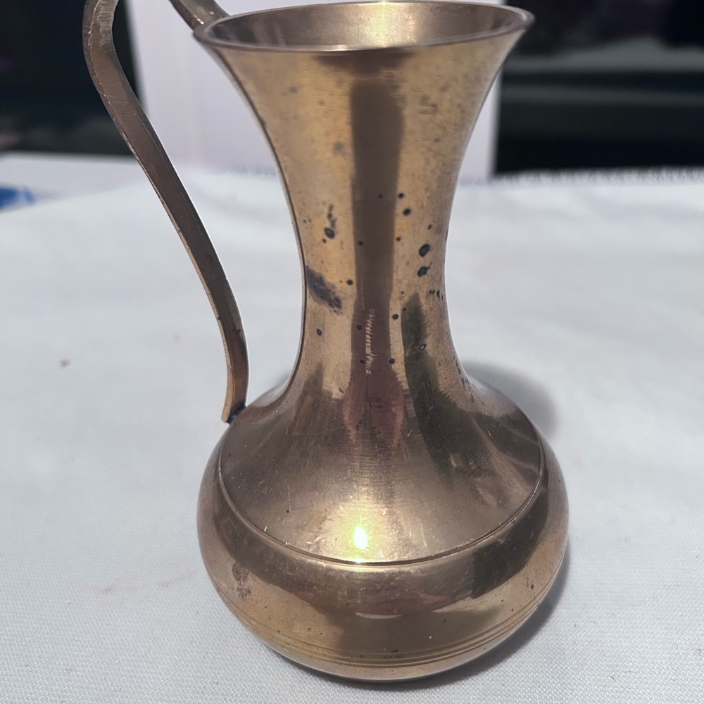A  small vintage Indian brass decorative pitcher with a curved handle.- preloved